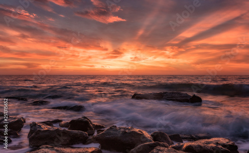 First light. Stunning seascape with motion blur and flowing waves at the rocks