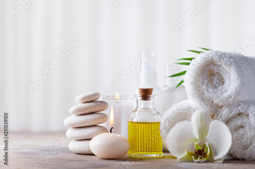 Spa, beauty treatment and wellness background with massage pebbles, orchid flowers, towels, cosmetic products and burning candles.
