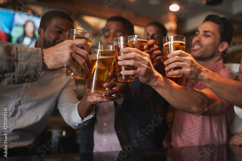 Group Of Male Friends On Night Out For Bachelor Party In Bar Making Toast Together