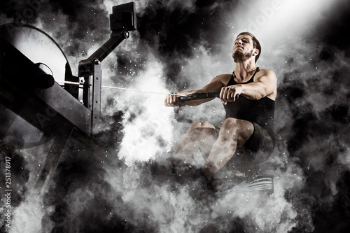 Bearded fit man using rowing machine