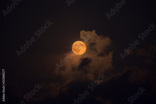 Pleine lune rousse au milieu des nuages de nuit