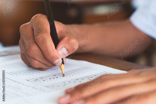 School student is taking exam and writing answer in classroom for education test concept