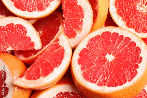 Many sliced fresh ripe grapefruits as background, closeup