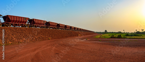 Railway carriages for transportation of bauxite ore on train tracks at the end of the railway line from bauxite mining. Guinea, Africa.