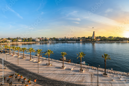 The Italian Sailor Monument, promenade and bay as the sun sets in the seaside port city of Brindisi Italy in the Southern region of Puglia.