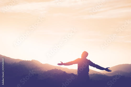 Copy space of man rise hand up on top of mountain and sunset sky abstract background.