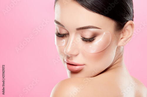 Cute girl with nude make up and naked shoulders at studio background, invisible eye patches on face, close up, beauty photo concept.
