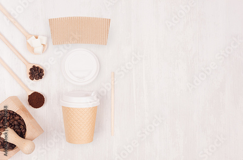 Decorative background for restaurant and coffee shop - blank paper cup, label, mortar with coffee beans, copy space on white wood board, top view, closeup.