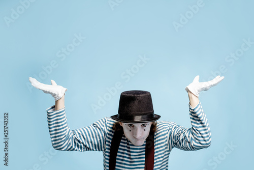 Emotional pantomime with white facial makeup showing empty space on the blue background, advertising something