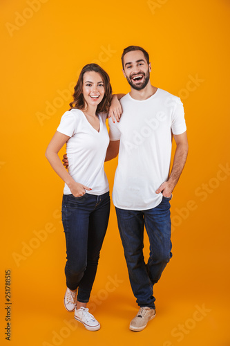 Full length photo of beautiful couple smilings while standing, isolated over yellow background