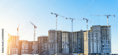 Large residential complex real estate apartments, under construction with high cranes. Panorama view