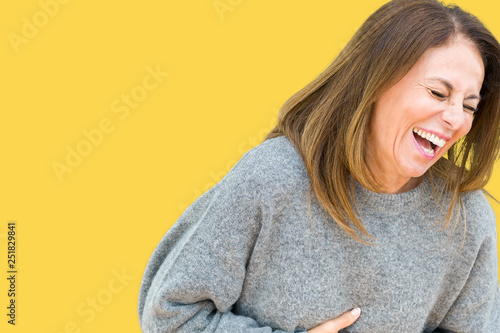 Beautiful middle age woman wearing winter sweater over isolated background Smiling and laughing hard out loud because funny crazy joke. Happy expression.