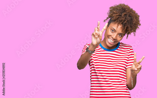 Beautiful young african american woman over isolated background smiling looking to the camera showing fingers doing victory sign. Number two.