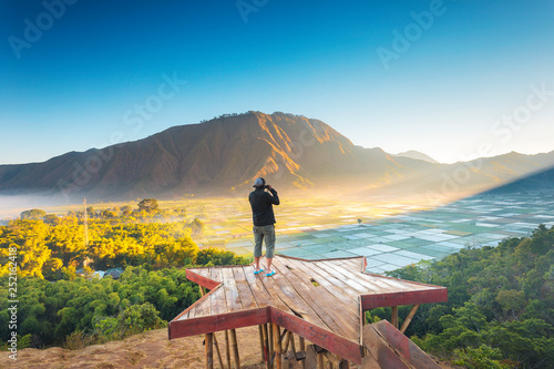 Traveller enjoying views and take a picture wonderful farmland scenery at Sembalun near Rinjani volcano in Lombok, Indonesia. Traveling, freedom and active lifestyle concept.