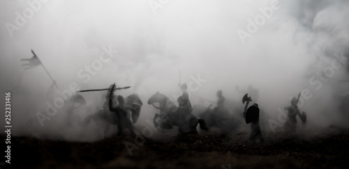 Medieval battle scene with cavalry and infantry. Silhouettes of figures as separate objects, fight between warriors on sunset foggy background.