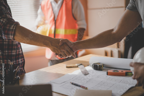 Successful deal, male architect shaking hands with client in construction site after confirm blueprint for renovate building.