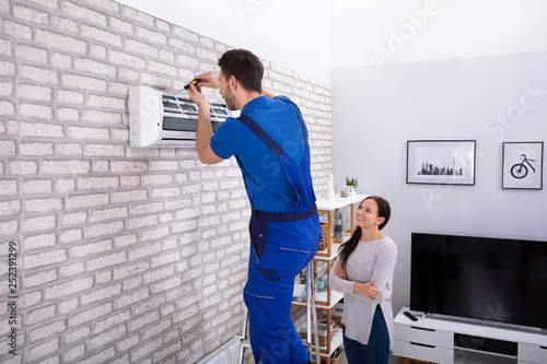 Male Technician Repairing Air Conditioner With Screwdriver