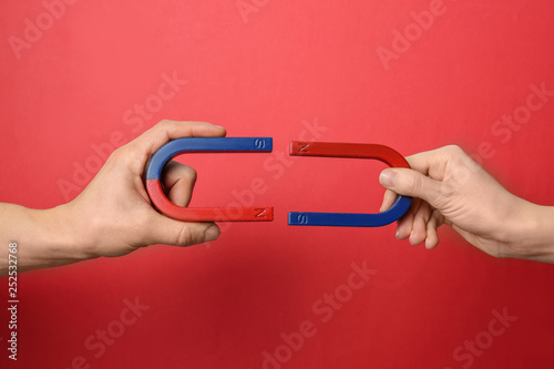 People holding magnets on color background, closeup