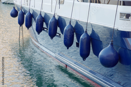 Closep of blue fenders hanging on blue and white boat in the harbor in Malta