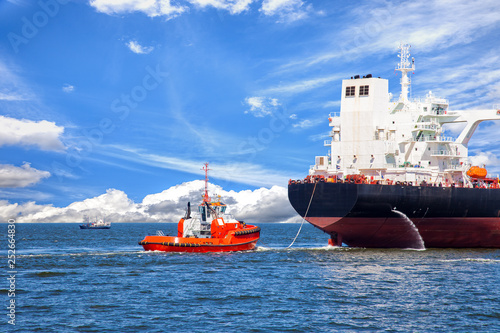 Tanker ship with escorting tug leaving port.