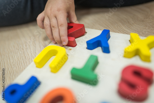 Child's hand playing with abc letters from colorful wood