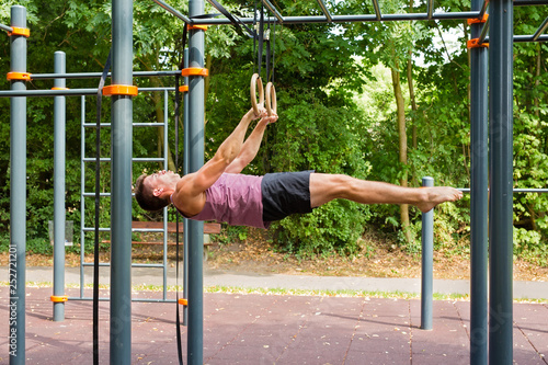 Handsome young man doing calisthenics ring workout.