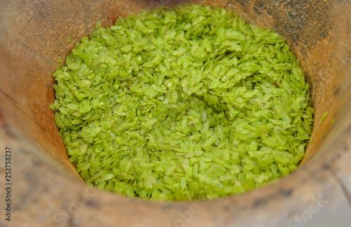 Rice green sweet pounded unripe rice flakes cereal in wooden mortar