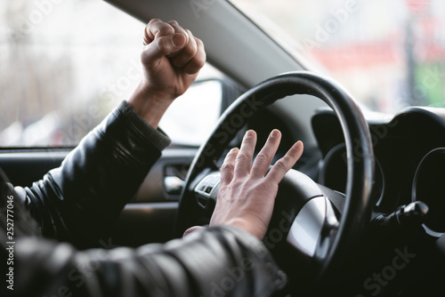 Angry driver is honking and is yelling by sitting of a steering wheel. Road aggression concept. Traffic jam.