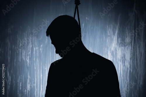 Male suicider with noose on his neck against grunge wall