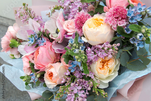 Beautiful rich elegant wedding pink bouquet, flowers arrangement by florist with roses, lilac and blue flowers. Floral background