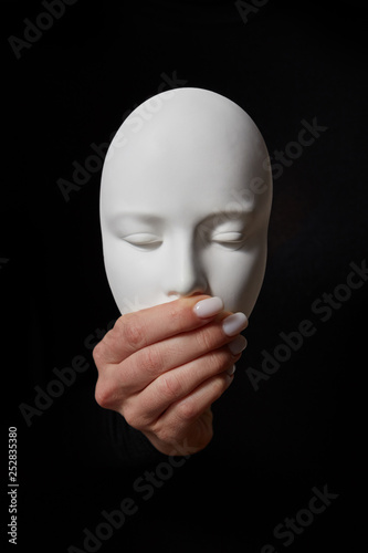 Plaster face mask with closed mouth on a black background. Speak no evil. Concept three wise monkeys