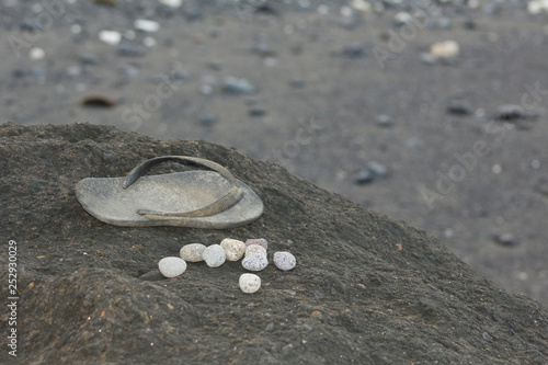A once-white thong and some pebbles sit on a black rock, abondoned playthings of a child.