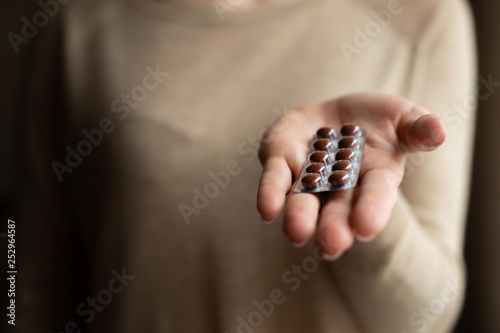 The girl is holding plates with pills on a dark background. Medicine and treatment