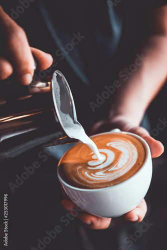 vintage tone of some people pour milk to making latte art coffee at cafe or coffe shop