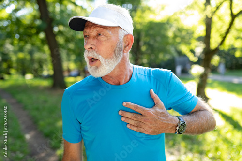 Senior man with chest pain suffering from heart attack during jogging