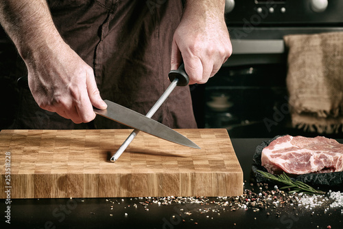 Closeup of male chef hands sharpen a big chef's knife