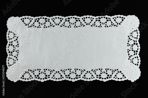 White paper lace doily, closeup on black background.