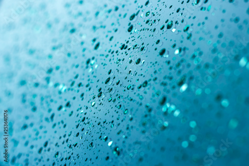 Drops of water on a bluish-green metallic surface