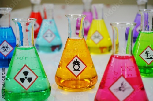 Many of Erlenmeyer flask with colorful solution and Variety type of chemical hazard warning symbols labels. Focus on Oxidizing sign,symbol.