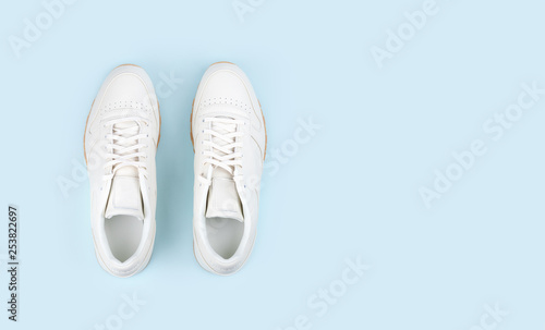 pair of white sneakers on blue background