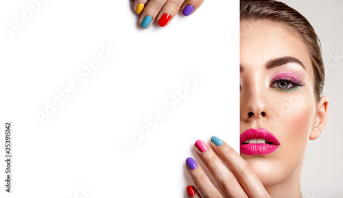 Beautiful woman with a colored manicure holds blank poster.
