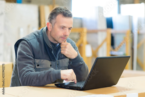 male worker looking at laptop in workshop