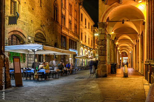 Old narrow street with arcade in Bologna, Emilia Romagna, Italy. Night cityscape of Bologna.