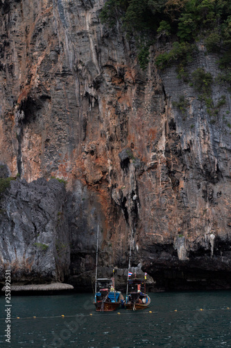 Long tail boat in front of tall cliffs in thailand