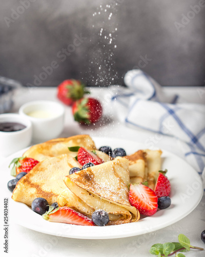 Thin pancakes with strawberries and blueberries, jam, condensed milk, delicious Breakfast. Russian traditional dessert for Shrovetide celebration (maslenitsa). French crepes