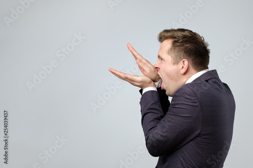 Caucasian man in suit making bla bla sign with his hand.