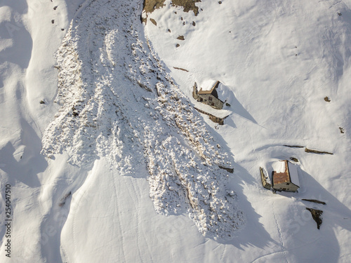 Aerial view of snow avalanche on mountain slope. Wet snow in spring sliding downhill.