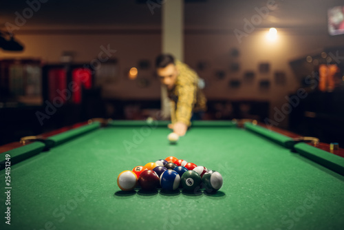 Male billiard player with cue aiming at the table