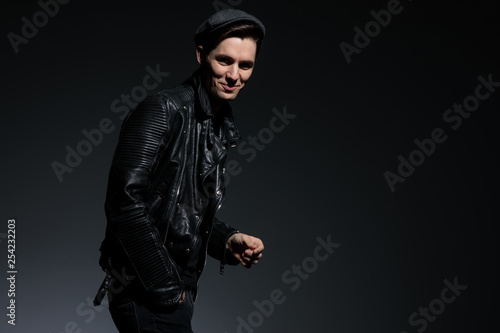 laughing young fashion man in leather jacket and hat