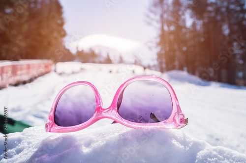 Colorfull of Pink sunglasses placed on snow at sport in ski resort valley with pine, landscape of winter time in at Fujiten ski resort, Japan